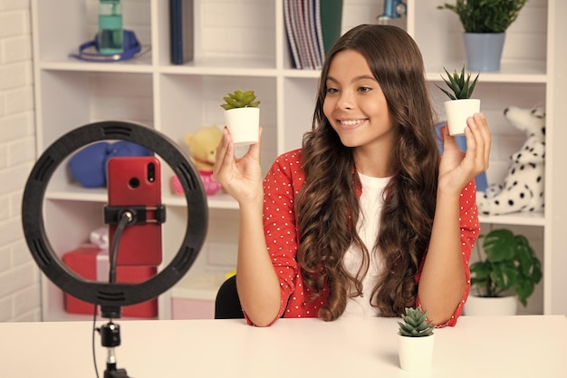 Criança adolescente gravando tutorial em vídeo para mídias sociais com smartphone Influenciador adolescente criando novo conteúdo para blog enquanto transmite online Garota feliz rosto positivo e sorridente