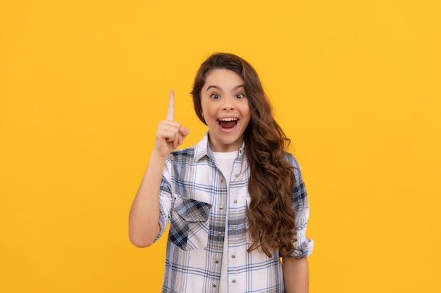 Criança adolescente inspirada na camisa quadriculada com cabelo longo encaracolado em fundo amarelo