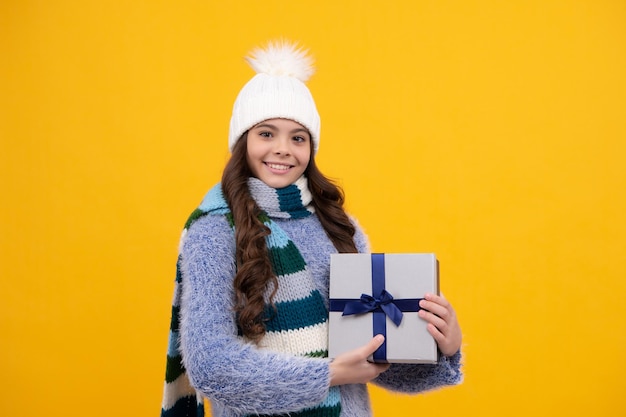 Criança adolescente segurando a caixa de presente em fundo amarelo isolado Presente para aniversário de crianças Caixa de presente de Natal ou Ano Novo Garota feliz enfrenta emoções positivas e sorridentes