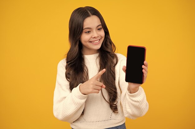 Criança adolescente usando telefone celular conversando na web Aplicativo móvel para smartphone Conceito de estilo de vida infantil Garoto mostrando o espaço de cópia de maquete de celular de tela em branco