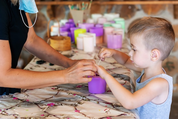 Criança adorável com artesão aparando pavios de velas em velas caseiras