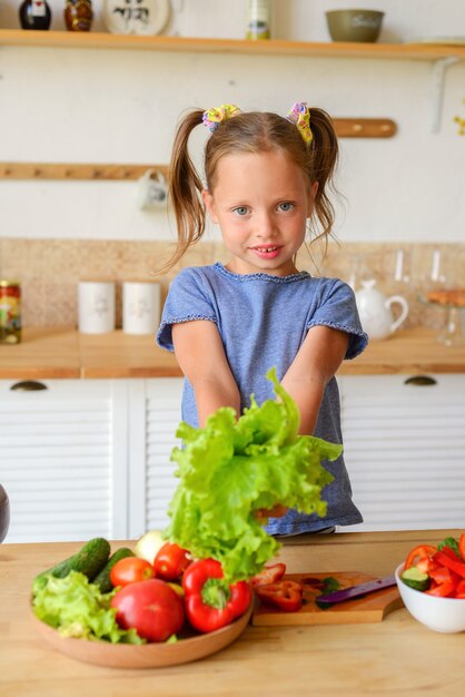 Criança adorável cozinhando na cozinha. Menina bonita preparando sopa