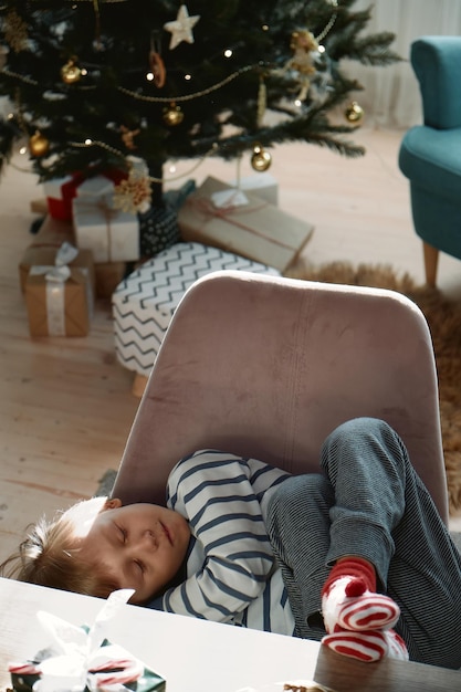 Criança adormecida esperando por presentes de Natal na manhã de Natal