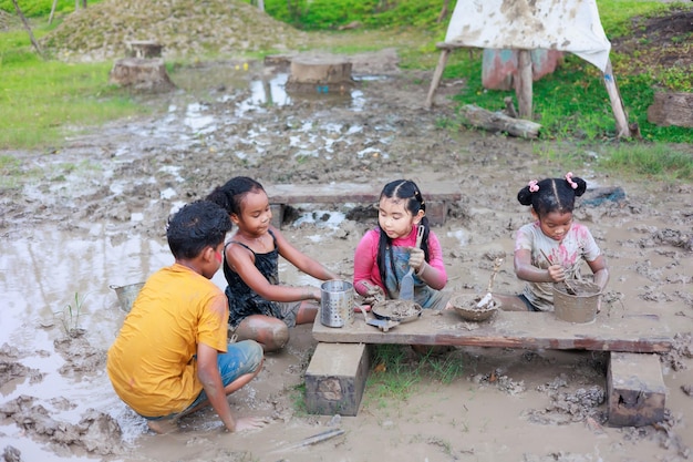 Criança africana e menina asiática brincando na lama poça juntos no acampamento de verão ao ar livre aprendendo