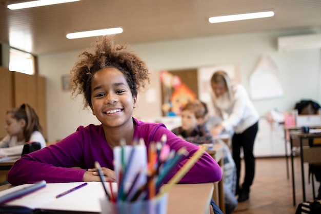 Criança afro-americana sentada na sala de aula com colegas e crianças ao fundo