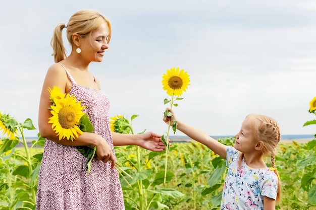 criança alegre dá a sua mãe flor de girassol em campo com girassóis, o conceito do feriado do Dia das Mães, horário de verão