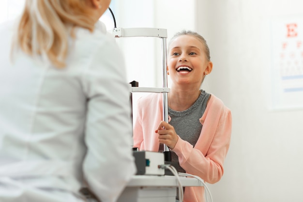 Criança alegre e animada com um sorriso largo conversando com um médico simpático