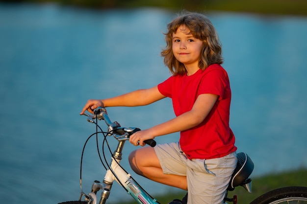 Criança andando de bicicleta Crianças esportes e atividades Criança feliz Criança menino andando de moto no parque de verão Crianças bicicleta
