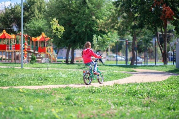 Criança andando de bicicleta em um parque de verão