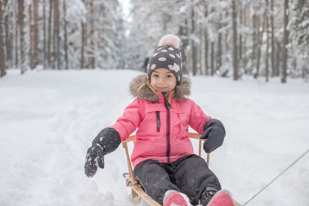 criança andando de trenó na floresta de inverno