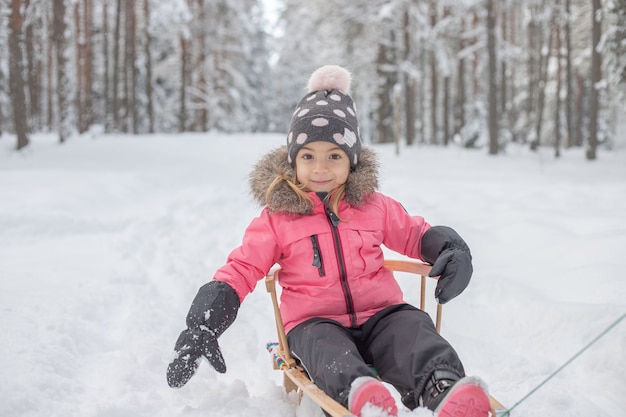 criança andando de trenó na floresta de inverno