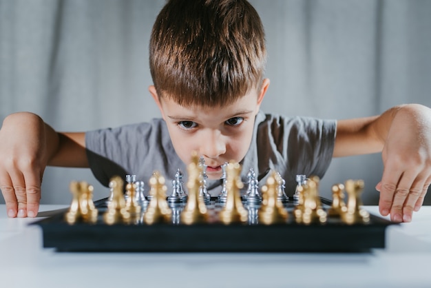 Criança aprende a jogar xadrez em seu quarto em casa