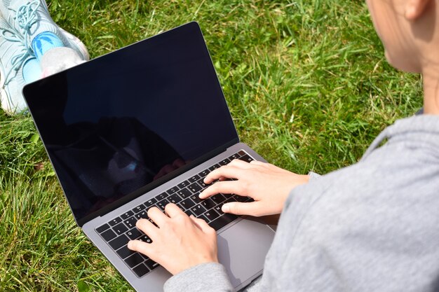 Criança aprende em um laptop ao ar livre