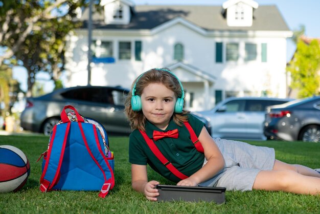 Criança aprendendo ao ar livre, estudando on-line e trabalhando em um tablet em campo verde