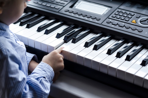 Criança aprendendo música ao piano. garota tocando teclados.