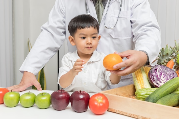 Criança aprendendo sobre nutrição com médico para escolher comer frutas e vegetais frescos.