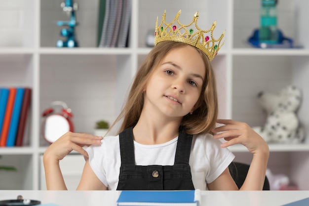 Foto criança arrogante na coroa de rainha na sala de aula da escola