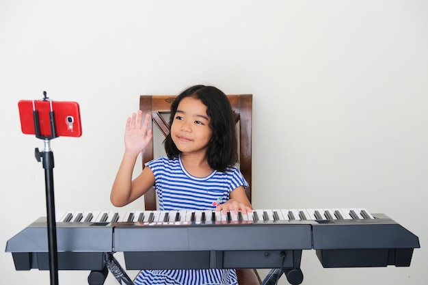 Foto criança asiática aprendendo a tocar piano online em casa