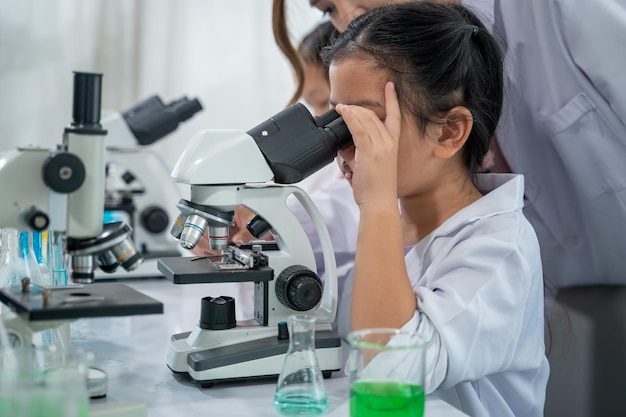 Criança asiática aprendendo com cientista no laboratório. Exame físico e aula de educação científica.