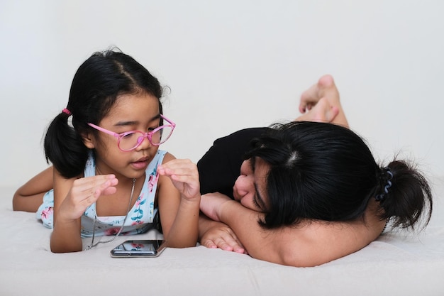 Foto criança asiática contando histórias para a mãe enquanto assiste a um filme no celular