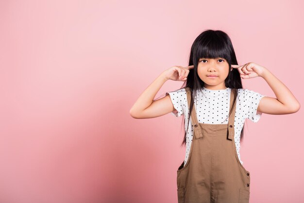 Criança asiática de 10 anos Feche os ouvidos com os dedos e os olhos