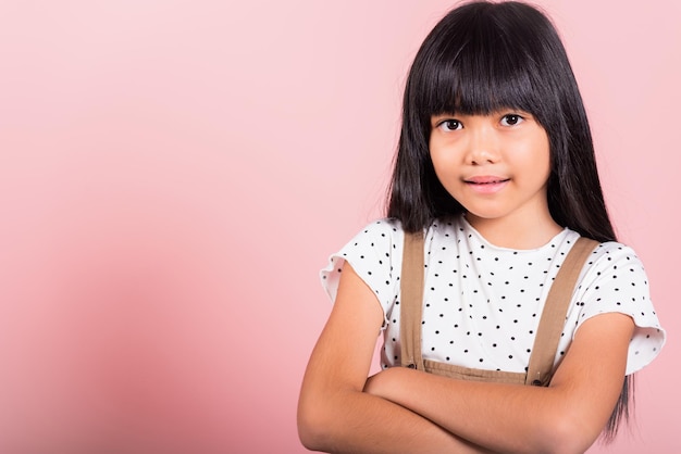 Criança asiática de 10 anos sorrindo com os braços cruzados