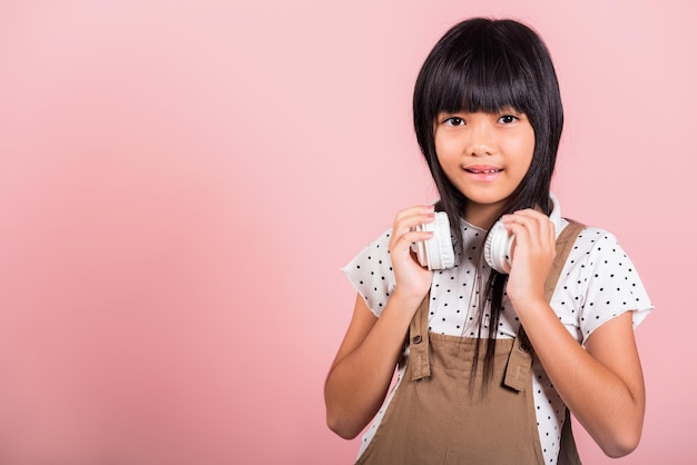 Criança asiática de 10 anos sorrindo ouvindo música usando fone de ouvido sem fio no pescoço