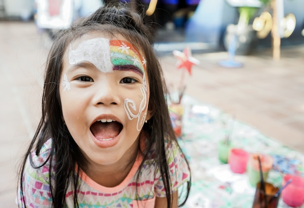 Criança asiática em idade pré-escolar com maquiagem facial