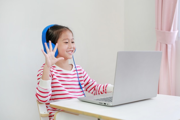 Criança asiática estuda aula de aprendizagem on-line por videochamada no laptop com o professor