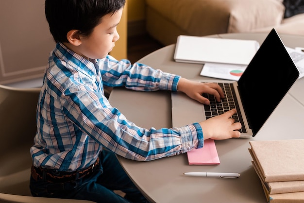 Criança asiática estudando online com laptop em casa durante a quarentena