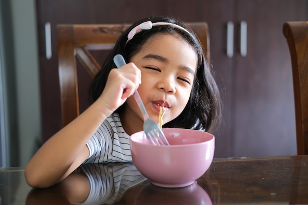 Criança asiática gostando de comer macarrão