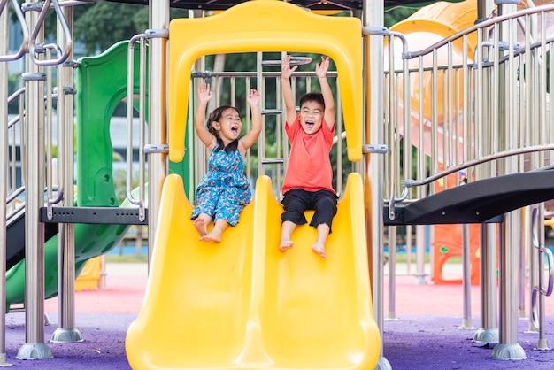 Criança asiática sorrindo brincando no playground ao ar livre do brinquedo da barra deslizante