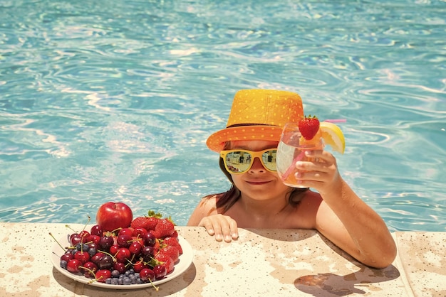 Criança bebe coquetel Criança na piscina com frutas Atividade infantil de verão Férias de verão Estilo de vida saudável para crianças