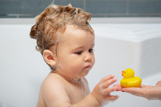 Criança bebê está lavando o cabelo no banho banho de espuma infantil