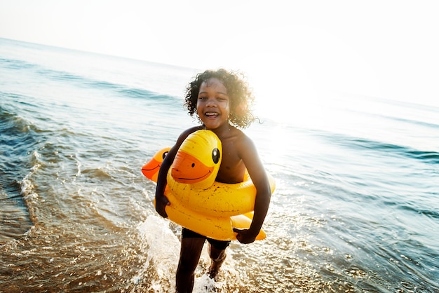 Criança bonita com tubo de pato na praia