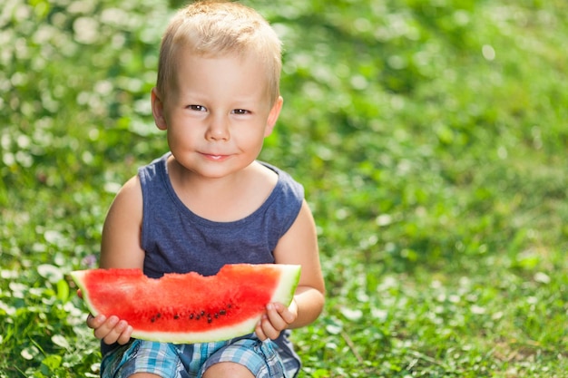 Criança bonita comendo uma fatia de melancia