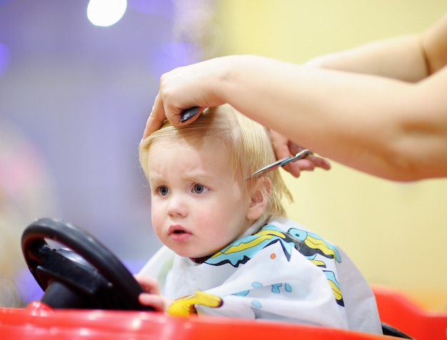 Criança bonita da criança, recebendo seu primeiro corte de cabelo