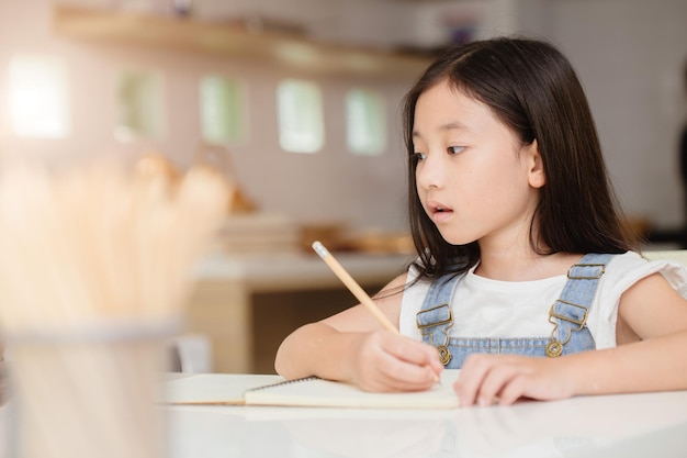 Criança bonita feliz aprendendo educação fazendo trabalhos de casa em férias em casa