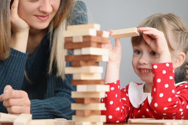 Criança bonita puxando um bloco de madeira para fora da torre e sorrindo