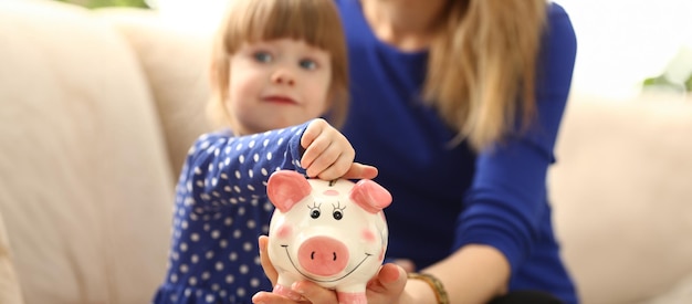 Criança braço de menina colocando moedas no cofre