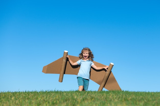 Criança brinca de astronauta ou criança piloto no fundo de crianças de céu azul com asas de papel jetp