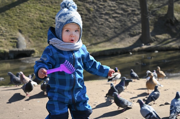 Criança brinca na rua com pombos. criança e pombos.