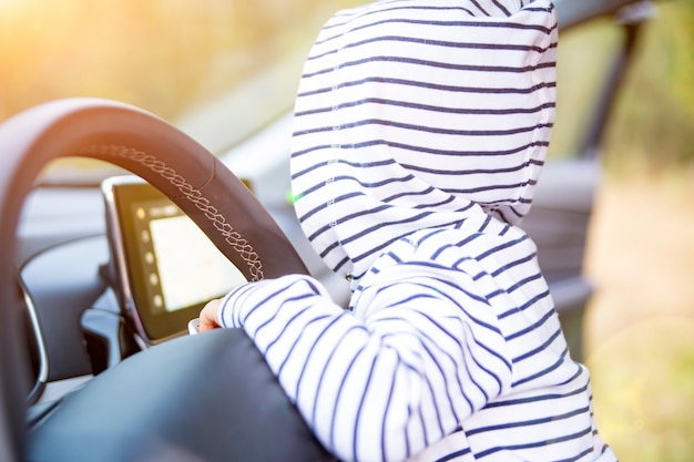 Criança brinca no volante de um carro moderno. close-up sem rosto. interior de um carro premium. conceito de jovem motorista