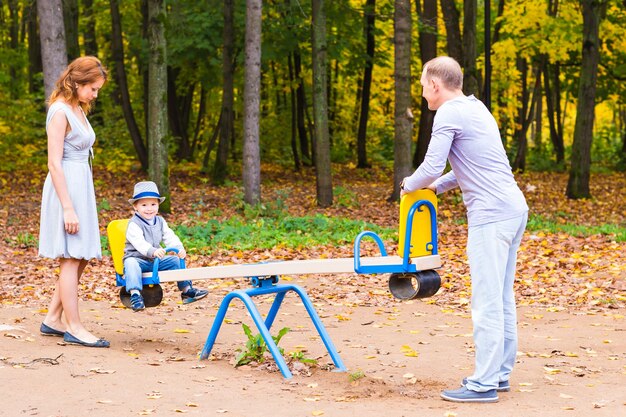 Criança brincalhona com os pais no playground ao ar livre. mãe, pai e filho