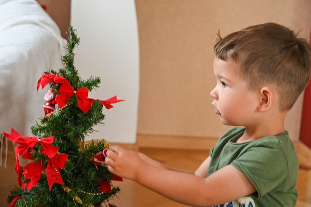 Criança brincando com árvore de Natal. Foto de alta qualidade