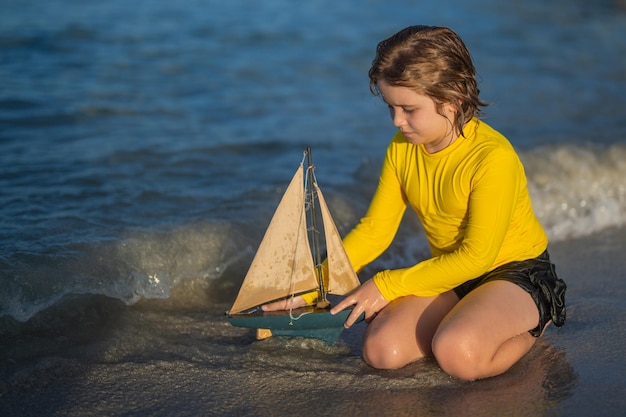 Criança brincando com barco de brinquedo nas ondas do mar na praia durante as férias de verão infância e verão