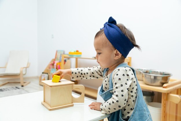 Criança brincando com caixa de forma quadrada montessori