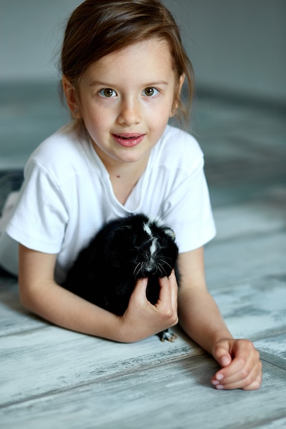 Criança brincando com cobaia. Garota cuida de animais de estimação.