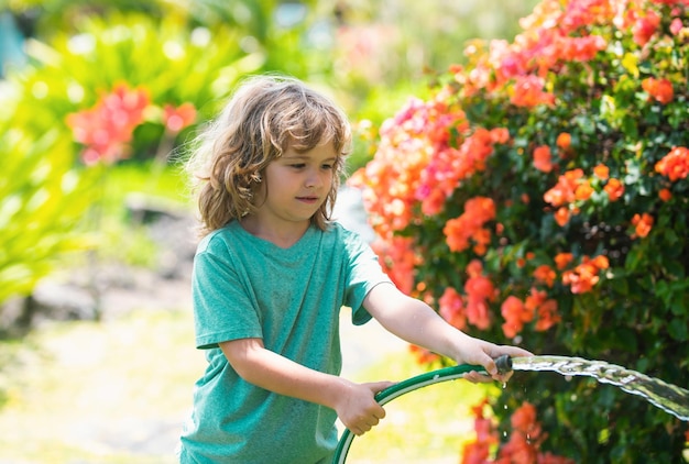 Criança brincando com mangueira de jardim no quintal engraçado garoto animado se divertindo com spray de água no quintal