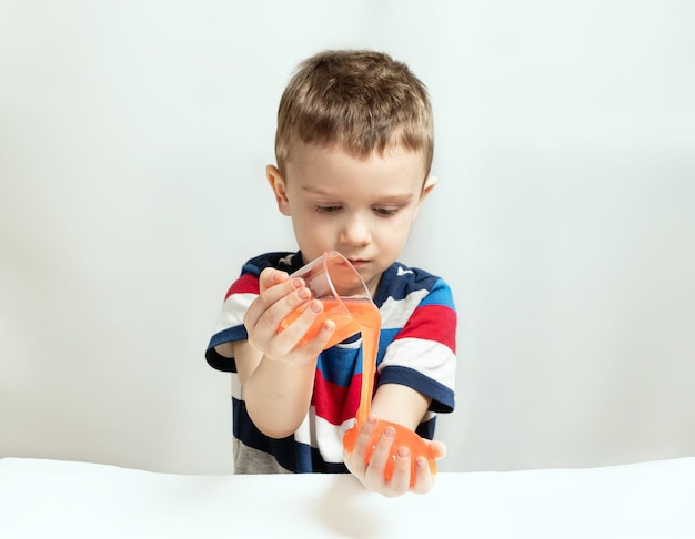 Criança brincando de brinquedo feito à mão chamado lodo Mãos de crianças brincando de brinquedo de lodo Fazendo lodo Foco seletivo